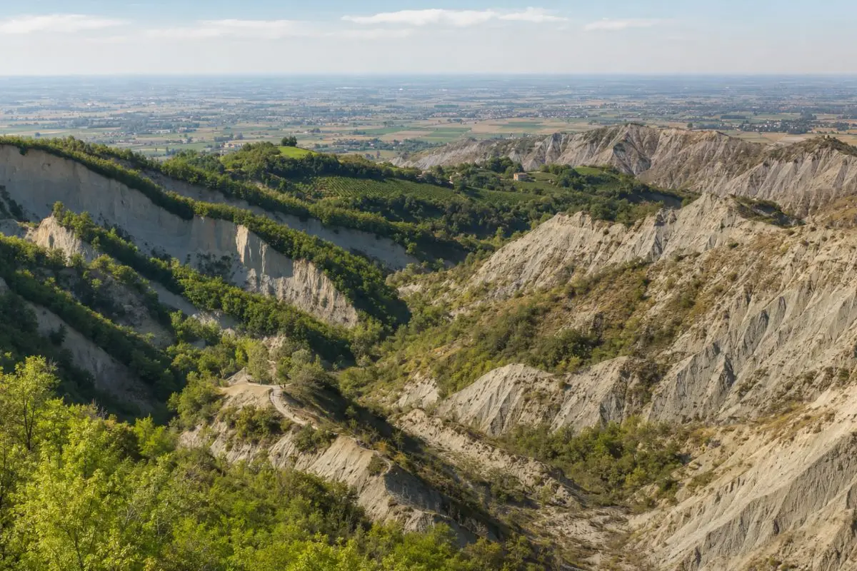 Orridi e calanchi dell’Oltrepò Pavese con pareti erose, creste argillose e colline verdi sullo sfondo.
