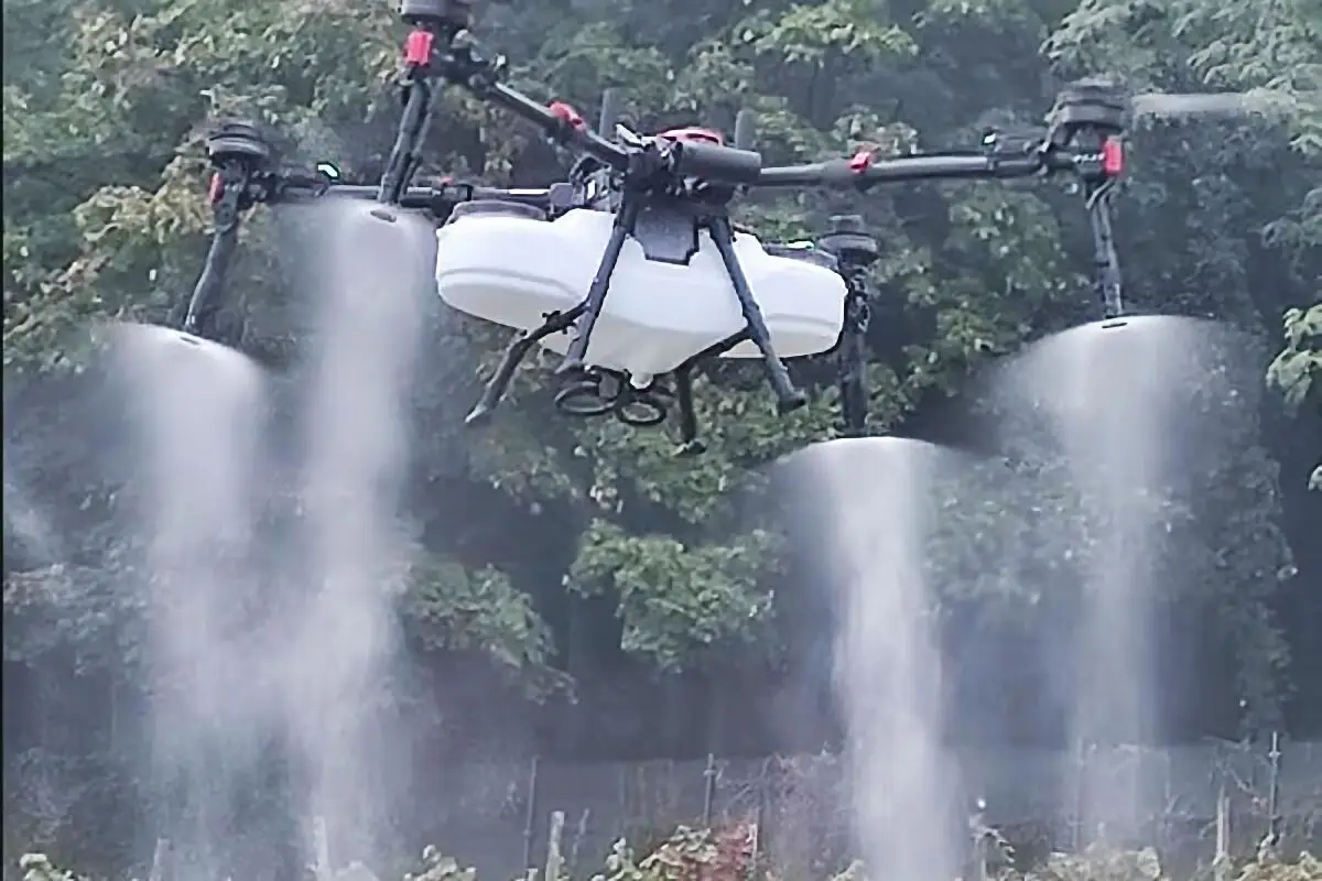 Droni in agricoltura: drone agricolo con serbatoio e quattro ugelli che nebulizza un trattamento di precisione sulle colture